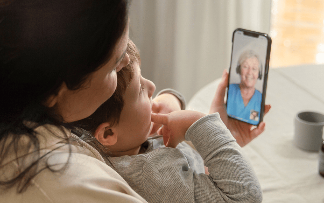 Barn som sitter i kvinnas famn. Pratar med Min vård Gävleborg i telefon.