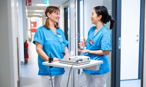 Två vårdmedarbetare diskuterar i korridor 