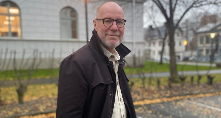 En man st&aring;r mitt p&aring; en gata och h&aring;ller i en portf&ouml;lj.