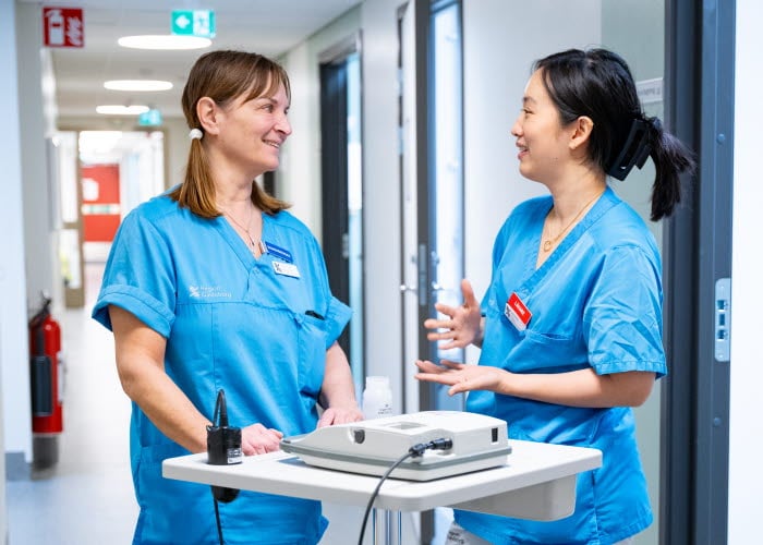 Två vårdmedarbetare diskuterar i korridor 